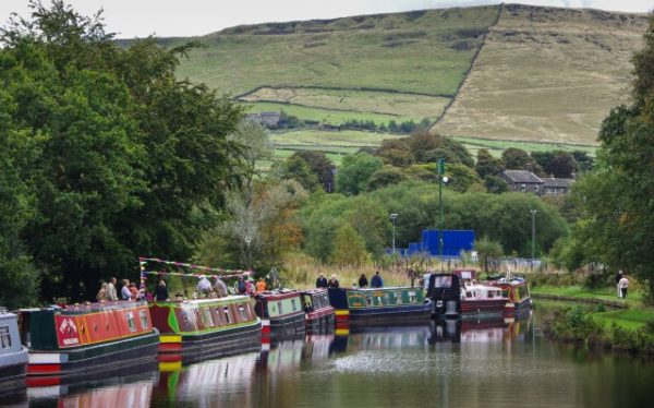Narrow boats on a canal beneath a hill