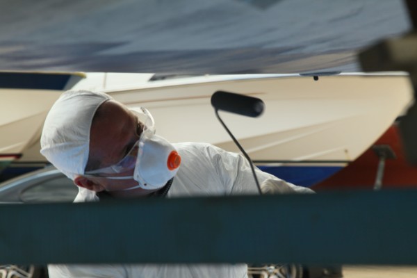 A person in protective clothing applying antifoul to the hull of a boat