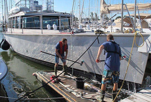 Two people cleaning the hull of a boat