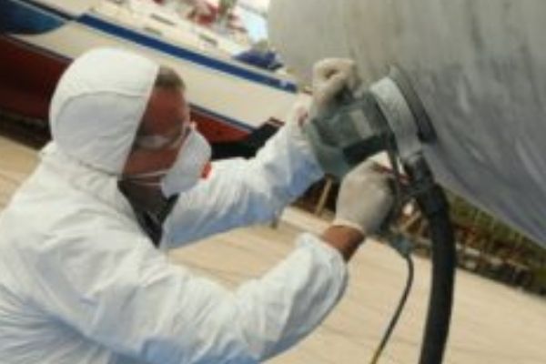 A person removing antifoul from a boat hull