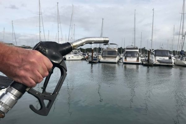 A fuel pump being held with boats in the background