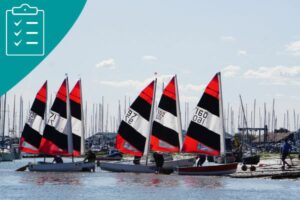 Boats with black and red sails launching from a beach