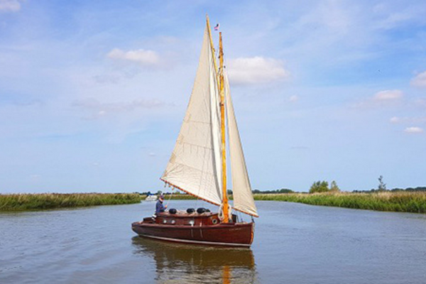 A sailing yacht on inland waters in the Norfolk Broads