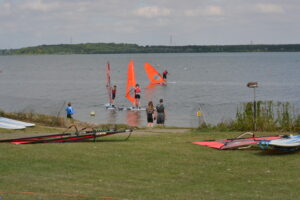 A group of windsurfers are lining up for a race. 
