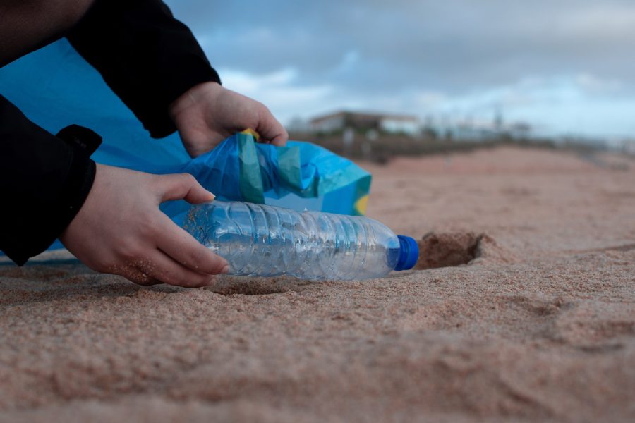 A bottle is being picked up from the sand.